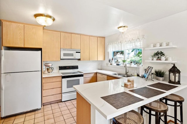kitchen with white appliances, light brown cabinetry, a sink, a peninsula, and light countertops