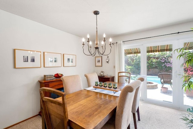 dining room with light carpet, a chandelier, and baseboards