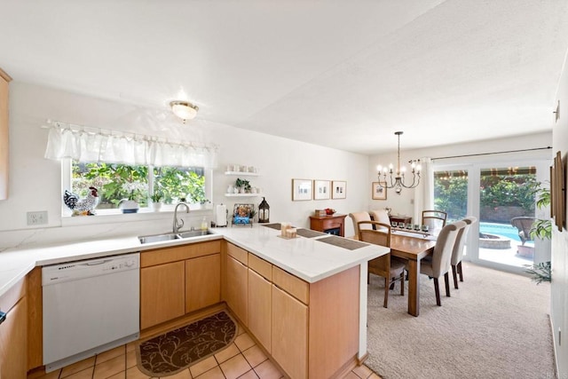 kitchen featuring white dishwasher, a sink, light countertops, a peninsula, and healthy amount of natural light