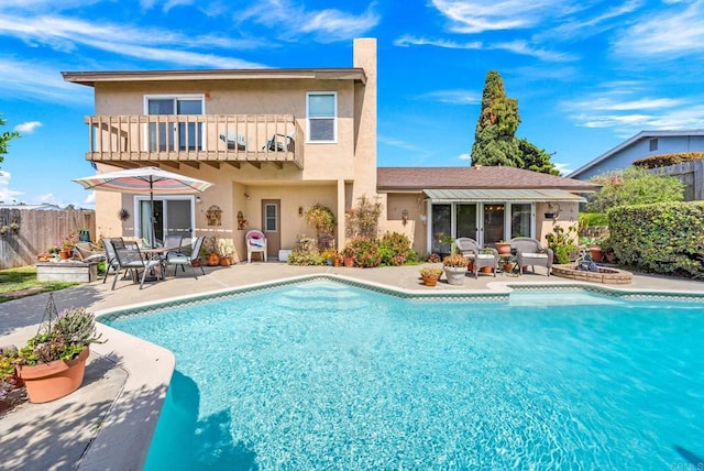 rear view of house featuring a balcony, a patio area, stucco siding, fence, and outdoor dining space