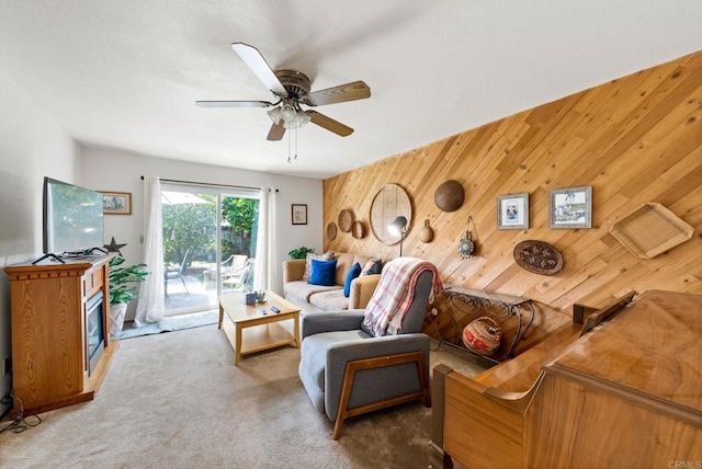 carpeted living area featuring a ceiling fan and wooden walls