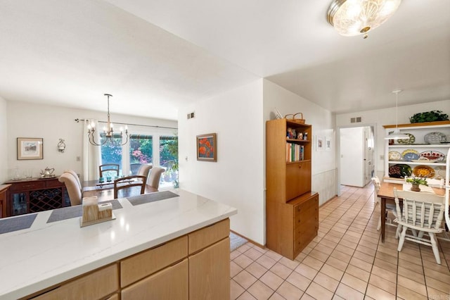 kitchen featuring a chandelier, light tile patterned flooring, hanging light fixtures, light stone countertops, and light brown cabinetry