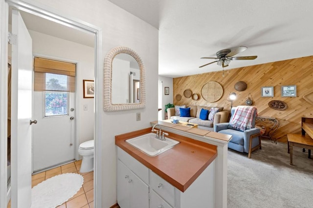 bathroom with wood walls, a ceiling fan, vanity, toilet, and tile patterned floors
