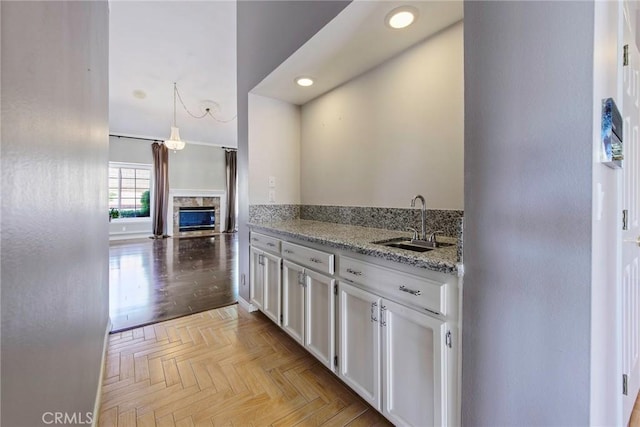 16350 Ridge View Dr, Apple Valley, CA 92307 - kitchen with a sink, white cabinets, recessed lighting, a stone fireplace, and light stone countertops