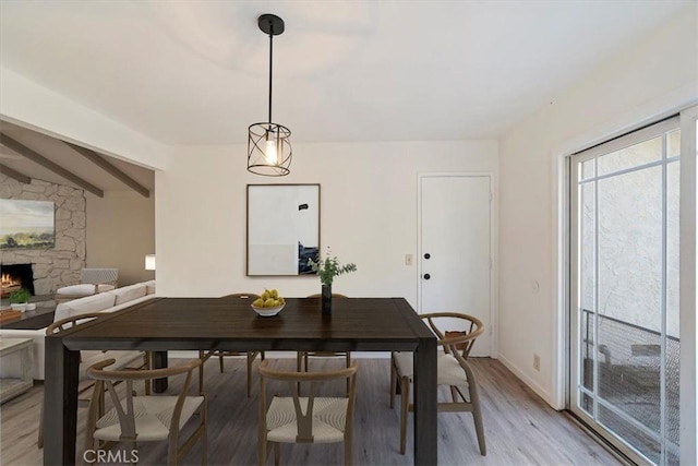 4180 Mount Baldy Ct, Norco, CA 92860 - dining area with a stone fireplace, light wood-type flooring, beam ceiling, and baseboards