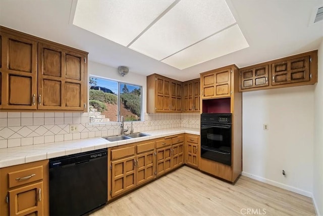 4180 Mount Baldy Ct, Norco, CA 92860 - kitchen with black appliances, a sink, a warming drawer, light wood finished floors, and decorative backsplash
