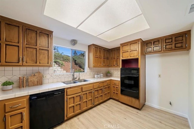 4180 Mount Baldy Ct, Norco, CA 92860 - kitchen with black appliances, a sink, a warming drawer, light wood-style flooring, and tasteful backsplash