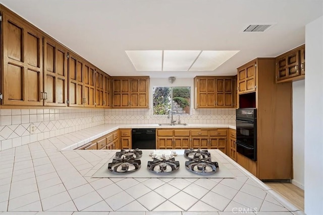 4180 Mount Baldy Ct, Norco, CA 92860 - kitchen with black appliances, a warming drawer, tile countertops, a sink, and decorative backsplash