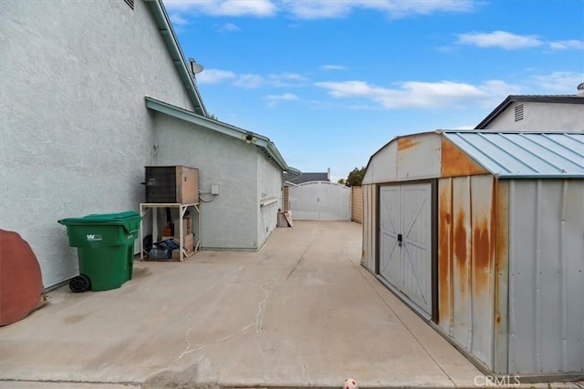 view of side of home featuring a storage shed, an outbuilding, a patio area, and stucco siding