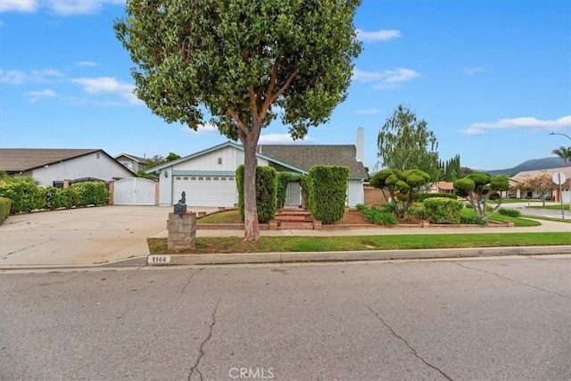 view of front of house featuring concrete driveway, a gate, a chimney, and an attached garage