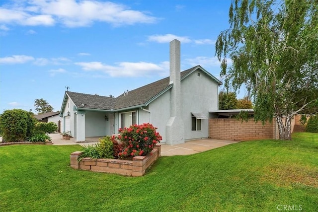 rear view of house featuring stucco siding, a yard, and a chimney