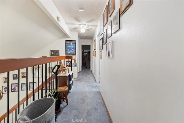 corridor featuring carpet flooring, baseboards, and a textured ceiling