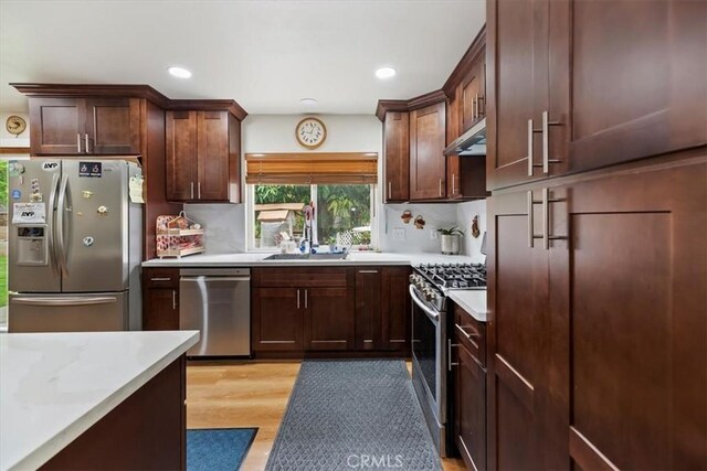 kitchen featuring appliances with stainless steel finishes, a sink, light countertops, light wood-style floors, and recessed lighting