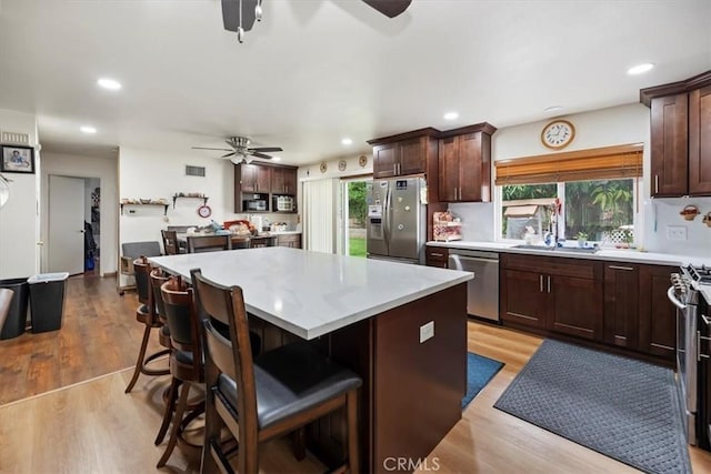 kitchen featuring stainless steel appliances, ceiling fan, a sink, light countertops, and a kitchen island