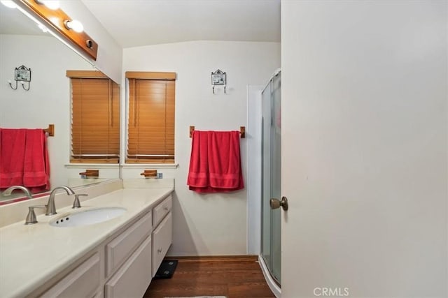 full bath featuring vanity, a shower stall, wood finished floors, and vaulted ceiling