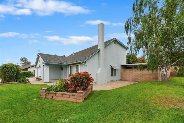 back of property featuring stucco siding, a chimney, and a yard