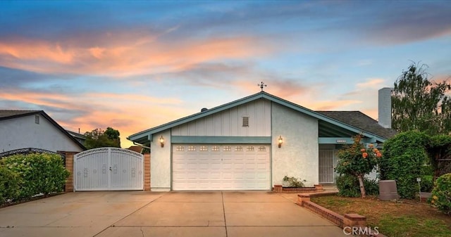 view of front of property featuring driveway, an attached garage, a gate, and a chimney