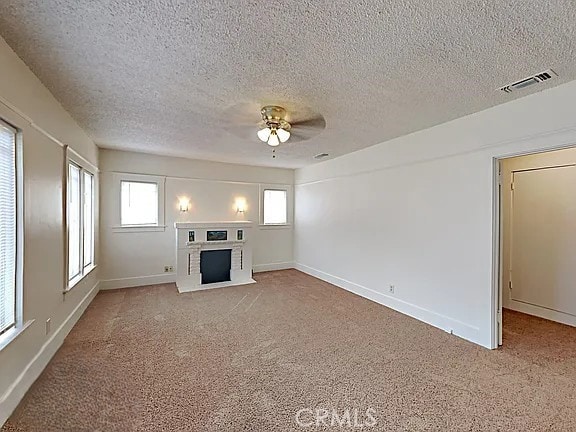 4890 7th Ave, Sacramento, CA 95820 - unfurnished living room with a fireplace, carpet floors, ceiling fan, a textured ceiling, and baseboards