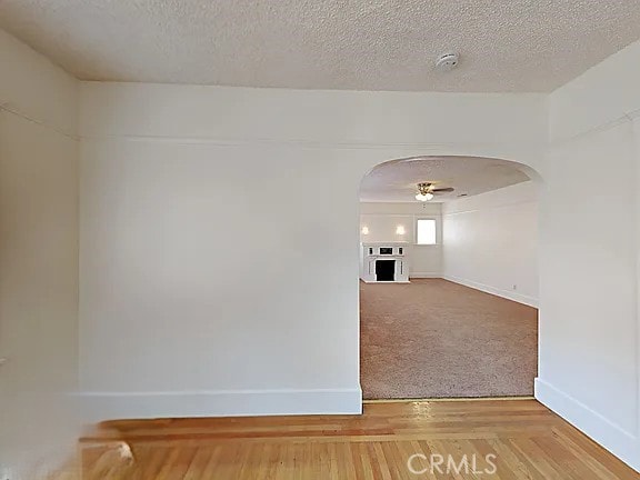 4890 7th Ave, Sacramento, CA 95820 - unfurnished room with arched walkways, baseboards, a textured ceiling, a fireplace, and a smoke detector