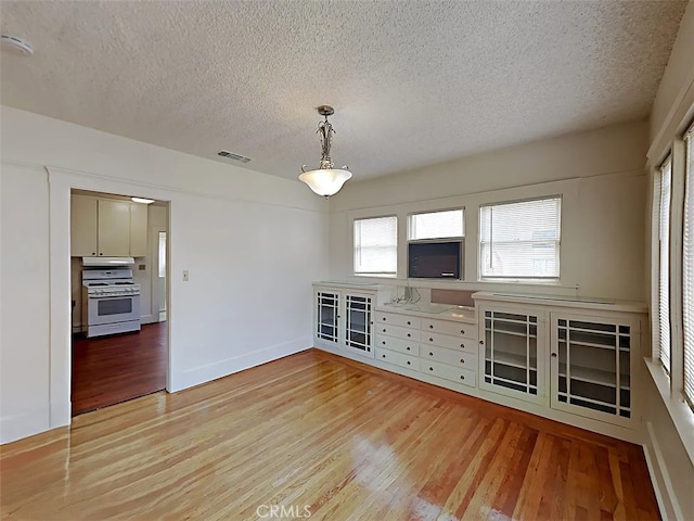 4890 7th Ave, Sacramento, CA 95820 - unfurnished dining area with light wood finished floors, a textured ceiling, and baseboards