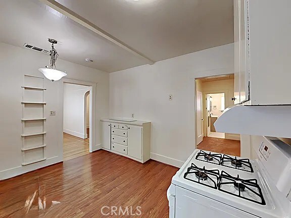 4890 7th Ave, Sacramento, CA 95820 - kitchen with white range with gas stovetop, wood finished floors, arched walkways, baseboards, and pendant lighting