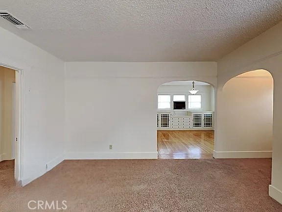 4890 7th Ave, Sacramento, CA 95820 - carpeted spare room with arched walkways, a textured ceiling, and baseboards