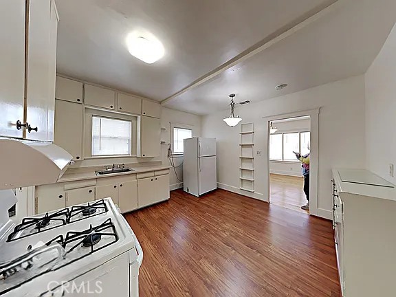 4890 7th Ave, Sacramento, CA 95820 - kitchen with white appliances, light countertops, a sink, dark wood-style flooring, and white cabinets