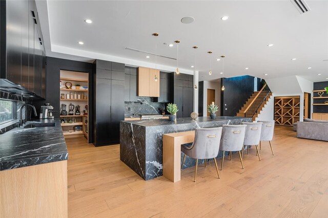 5141 Varna Ave, Sherman Oaks, CA 91423 - kitchen with modern cabinets, light wood-type flooring, backsplash, a kitchen bar, and a spacious island