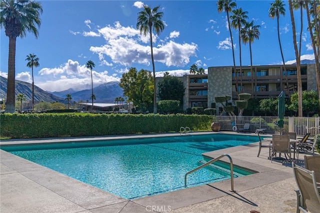 community pool featuring a mountain view, fence, and a patio area
