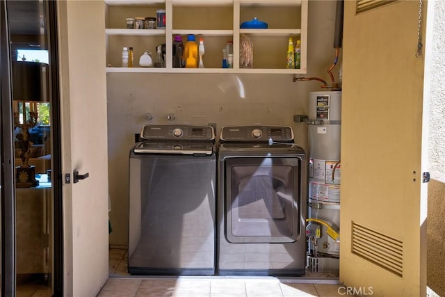 washroom with strapped water heater, washing machine and dryer, and tile patterned flooring
