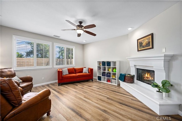 living room featuring ceiling fan, wood finished floors, a glass covered fireplace, baseboards, and recessed lighting