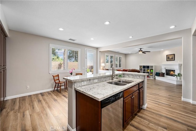 kitchen featuring dishwasher, a sink, light wood-type flooring, open floor plan, and a ceiling fan