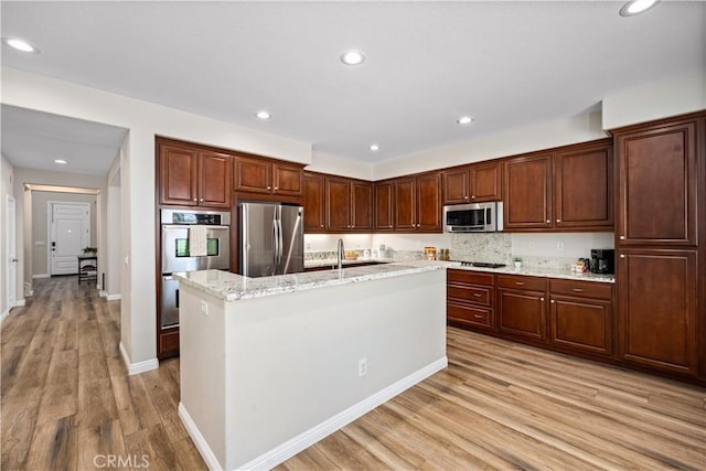 28264 Spring Creek Way, Menifee, CA 92585 - kitchen featuring stainless steel appliances, light wood-type flooring, a center island with sink, light stone counters, and recessed lighting