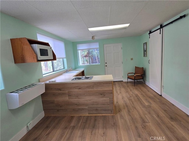 27403 Cottonwood Ln, Lake Arrowhead, CA 92317 - kitchen with a barn door, wood finished floors, baseboards, a drop ceiling, and a peninsula
