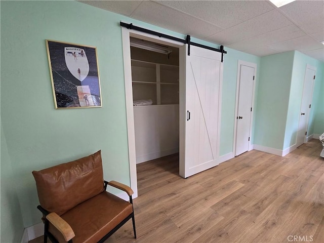 27403 Cottonwood Ln, Lake Arrowhead, CA 92317 - unfurnished room featuring light wood finished floors, a barn door, baseboards, and a paneled ceiling