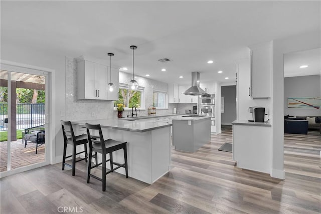 2612 Chauncy Pl, Riverside, CA 92506 - kitchen featuring island range hood, a peninsula, light wood-type flooring, recessed lighting, and backsplash