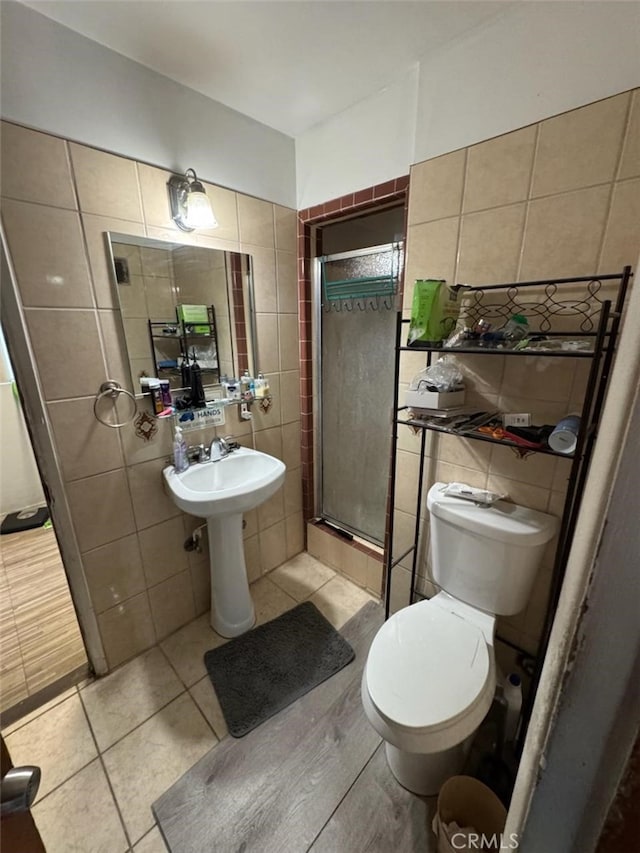 6045 Harding Ave, South Gate, CA 90280 - full bathroom with tile walls, toilet, a shower stall, and tile patterned floors