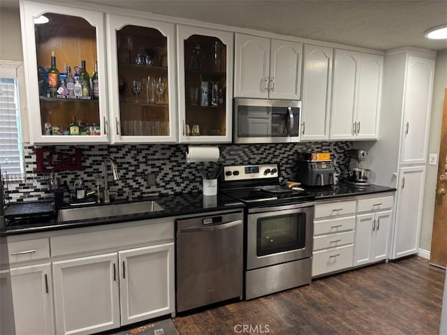 6045 Harding Ave, South Gate, CA 90280 - kitchen featuring stainless steel appliances, a sink, dark countertops, dark wood finished floors, and backsplash
