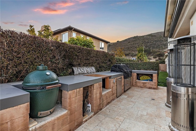 31740 Via Pamplona, San Juan Capistrano, CA 92675 - patio terrace at dusk with an outdoor kitchen, grilling area, fence, and a mountain view