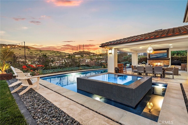 31740 Via Pamplona, San Juan Capistrano, CA 92675 - pool at dusk featuring an outdoor living space with a fireplace, a patio area, fence, an in-ground hot tub, and a gazebo