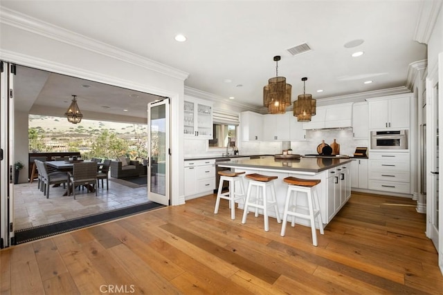 31740 Via Pamplona, San Juan Capistrano, CA 92675 - kitchen featuring appliances with stainless steel finishes, white cabinetry, a kitchen breakfast bar, a kitchen island, and crown molding