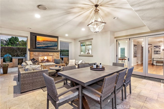 31740 Via Pamplona, San Juan Capistrano, CA 92675 - dining room with stone tile floors, recessed lighting, a stone fireplace, a chandelier, and french doors