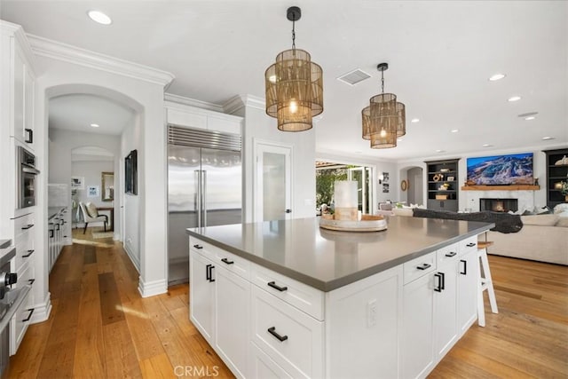 31740 Via Pamplona, San Juan Capistrano, CA 92675 - kitchen featuring arched walkways, stainless steel appliances, a lit fireplace, light wood finished floors, and dark countertops