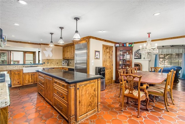 1585 E Ocean Blvd, Newport Beach, CA 92661 - kitchen featuring built in fridge, brown cabinets, tasteful backsplash, a chandelier, and crown molding