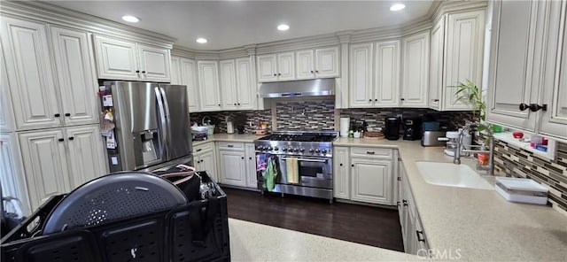 kitchen with stainless steel appliances, under cabinet range hood, a sink, light countertops, and backsplash