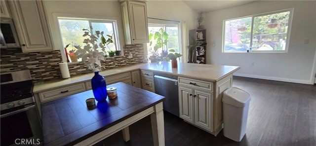 kitchen with dark wood-style floors, backsplash, dishwasher, light countertops, and a peninsula