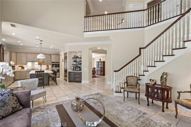 23478 Ridgeway, Mission Viejo, CA 92692 - living room featuring arched walkways, light tile patterned floors, a towering ceiling, stairway, and crown molding