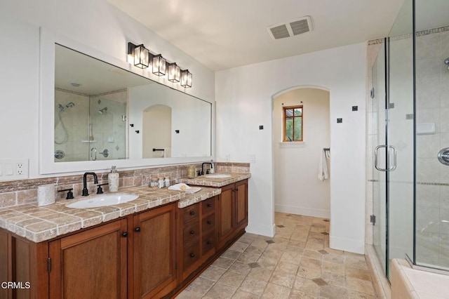 101 Via Tusa, Santa Barbara, CA 93105 - bathroom featuring a shower stall, baseboards, double vanity, tasteful backsplash, and stone finish flooring