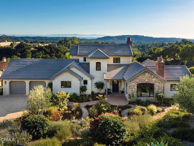 101 Via Tusa, Santa Barbara, CA 93105 - french country home featuring a chimney, an attached garage, stone siding, and stucco siding