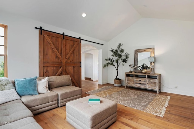101 Via Tusa, Santa Barbara, CA 93105 - living room featuring arched walkways, a barn door, wood finished floors, high vaulted ceiling, and baseboards